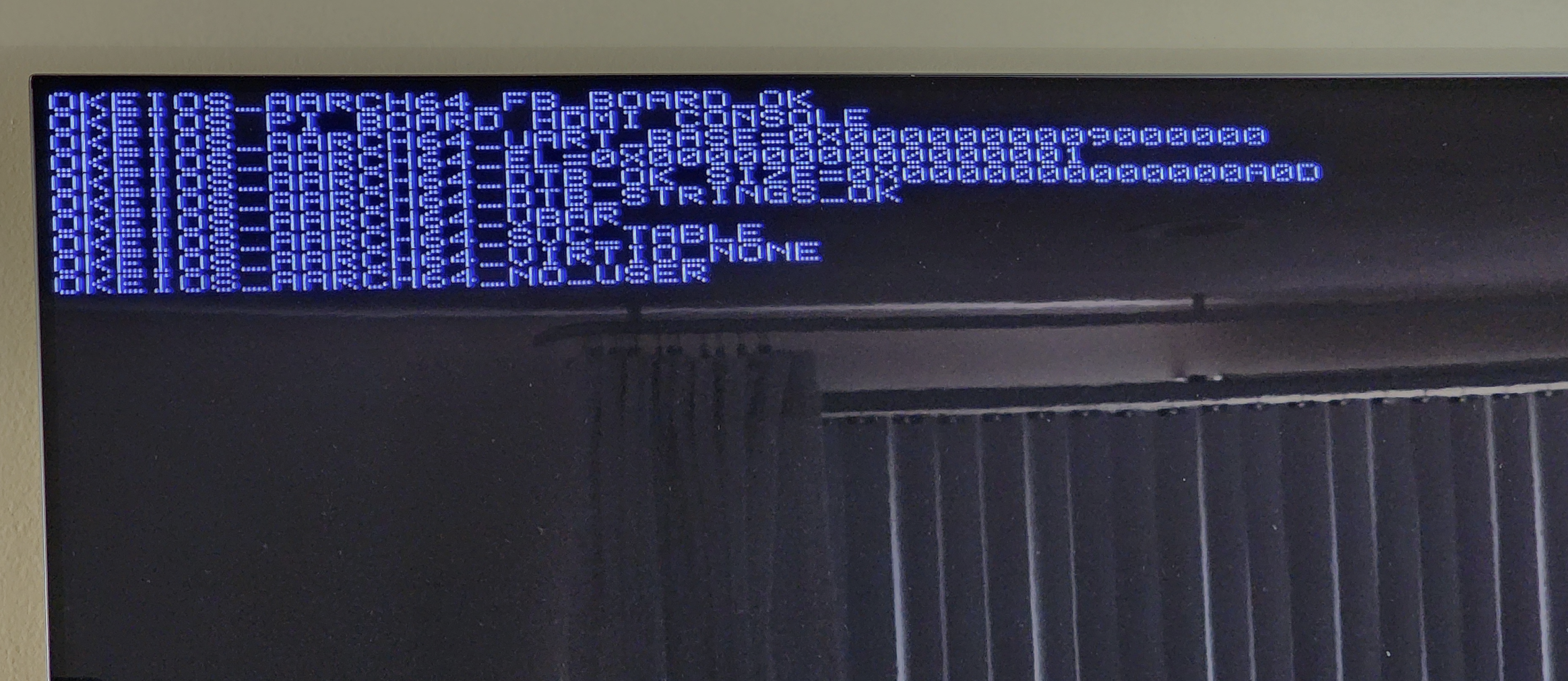 Physical monitor showing Okei OS AArch64 boot markers on a Raspberry Pi 5: OKEIOS_AARCH64_FB_BOARD_OK, OKEIOS PI BOARD HDMI CONSOLE, DTB_OK, VIRTIO_NONE, NO_USER